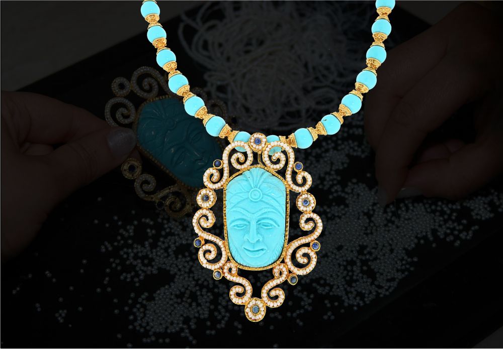 Collier in oro e pietre di turchese realizzato interamente a mano. Nella parte centrale è stata inserita una maschera in turchese circondata da elementi in oro realizzati interamente a mano.